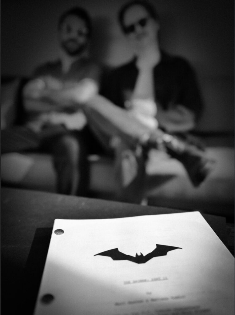 Black-and-white photo showing Matt Reeves and Mattson Tomlin blurred in background with a Batman Part II script in focus foreground